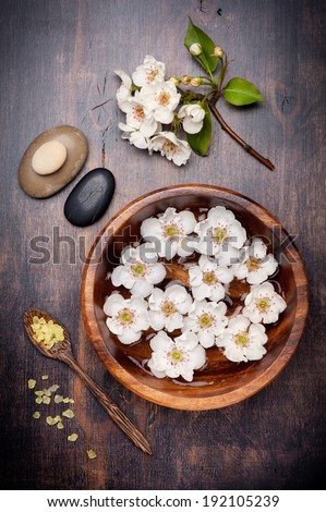 Flowers in bowl with water, zen stones for massage and sea salt. Spa and body care.