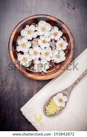 Flowers in bowl of water, towel, sea salt. Spa body care, manicure