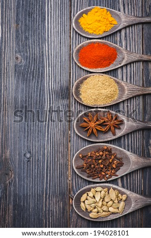 Spices in wooden spoons. Chili powder, turmeric, masala, cardamom, coriander, star anise