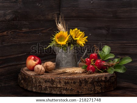 Flowers sunflower, wild rose, apple and walnuts on wooden board. Autumn Still Life