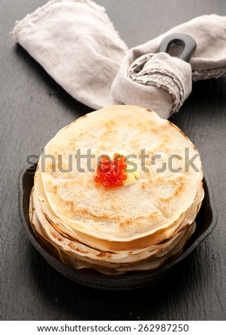 Pancakes with red caviar in frying pan
