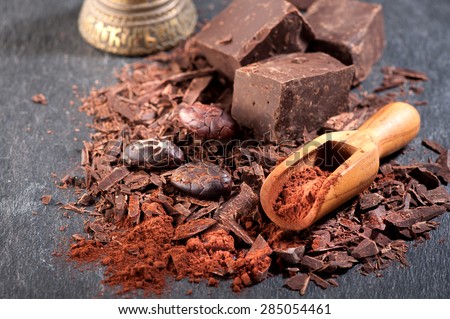 Chocolate, cocoa beans and cocoa powder on a stone background