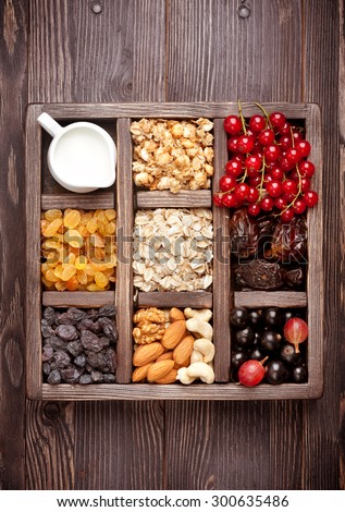 Granola, berries, nuts, dried fruit and milk. Healthy food in wooden box. Top view