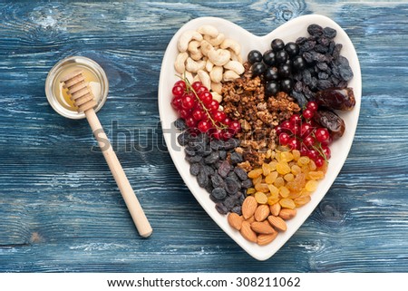 ingredients for healthy breakfast.  berries, nuts, granola, dried fruits, honey on wooden background, horizontal, top view