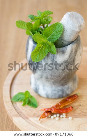 fragrant mint in a ceramic mortar and spices on wooden background