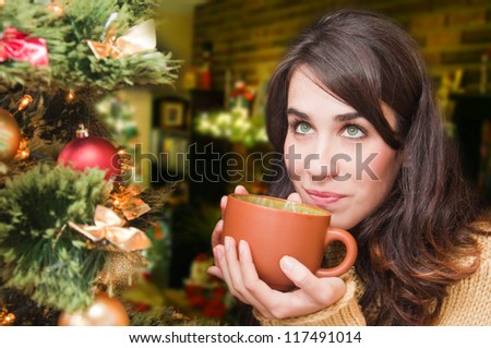 Young woman relaxing at home. Christmas time. Beautiful girl drinking tea at home.