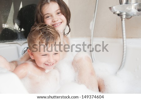 Brother and sister taking a bubble bath .
