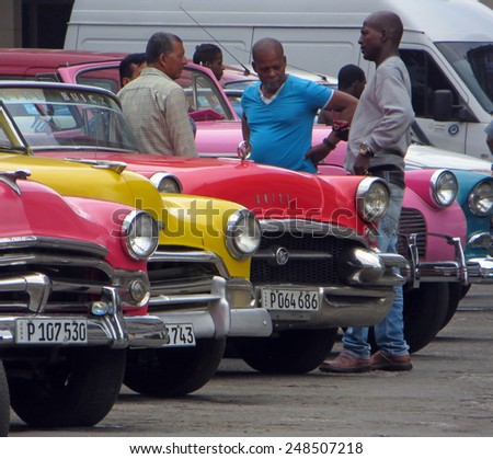 HAVANA, CUBA - APRIL 9, 2014: Drivers standing next to old cars waiting to drive tourists around Havana.