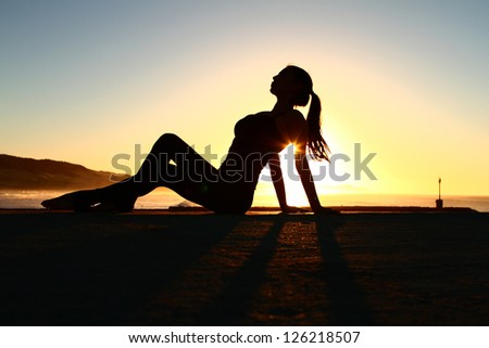 Silhouette of a sexy lady with sun rising over the sea/ ocean in the background.