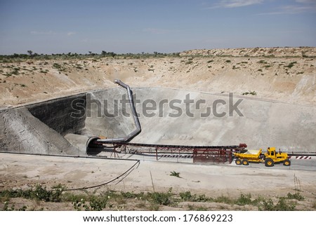 A mining vehicle is parked just outside on the entrance of an inclined diamond mine shaft in the desert