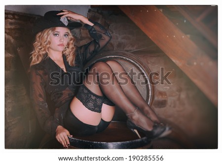 A beautiful young blonde lady is posing in an old pub and restaurant. She is wearing various Broadway performer outfits. Black lingerie and cowboy hat.