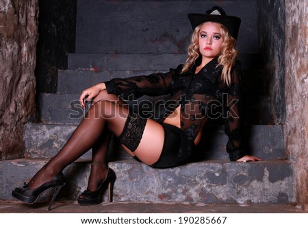 A beautiful young blonde lady is posing in an old pub and restaurant. She is wearing various Broadway performer outfits. Black lingerie and cowboy hat.
