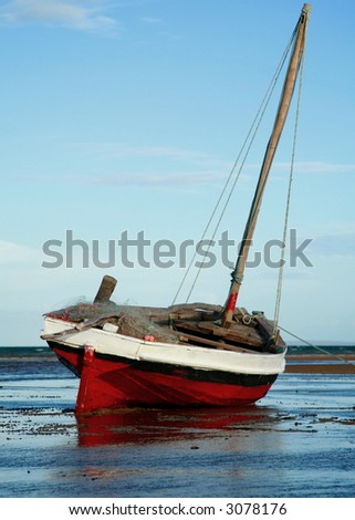 Red and White Sailing boat stranded at low tide in ocean at Vilanculos, Mozambique