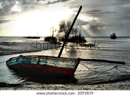 Red and White Dhow Sailing boat stranded at low tide in ocean at Vilanculos, Mozambique
