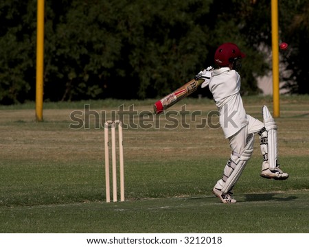 Young boy pulling or hooking a cricket ball during a match. Ball in the air, caught in motion