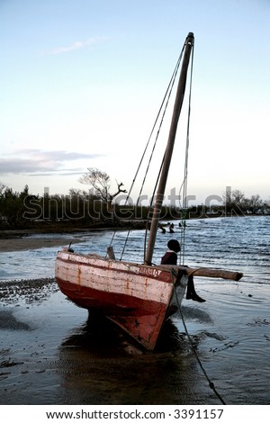 Young boy sitting on a dhow/ fishing boat/ sailing boat, waiting for his dad to return