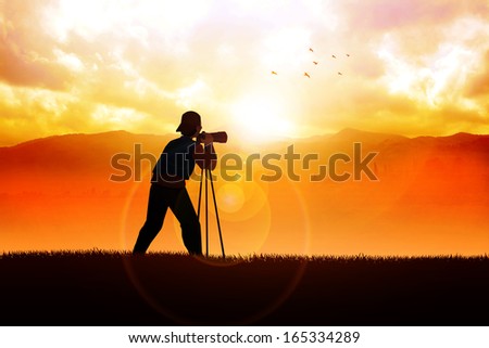 Silhouette of a photographer aiming his camera to the landscape