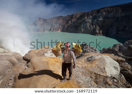 KAWAH IJEN, INDONESIA - AUGUST 11: Worker carries a basket with pieces of sulfur on his shoulder on August 11, 2013. Miners each carry up to 90kg of sulfur up steep cliffs at Kawah Ijen volcano.