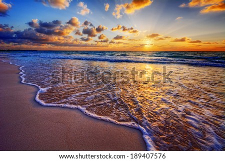 Colorful ocean beach sunrise with deep blue sky and sun rays