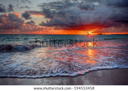 Brilliant sandy ocean beach sunset with dark ominous clouds