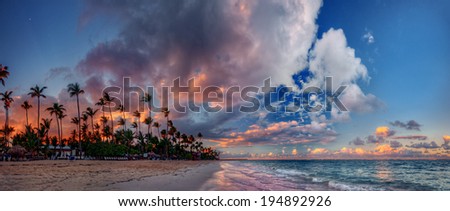 Panoramic ocean bay sunset with spectacular clouds, palm trees, and azure waters