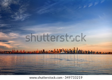 Sun painting the city skyline gold, blue water and sky