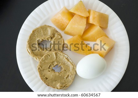 Healthy Organic High Protein Breakfast, Whole Wheat Bagel with Peanut Butter, Hard Boiled Egg and Cantaloupe isolated black