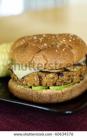 Spicy Black Bean Veggie Burger Topped with Melted Swiss Cheese, Sauteed Garlic Mushroom, and Avocado Slices on a Toasted Whole Wheat Bun