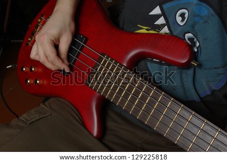 Playing on bass guitar with red body