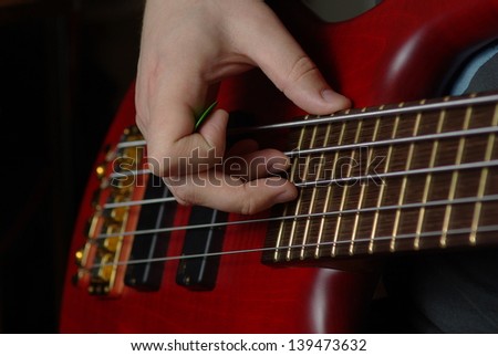 Playing on bass guitar with red body