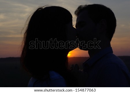 Silhouette sweethearts kissing at sunset