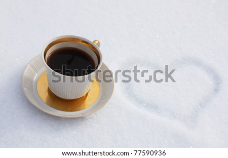 Heart drawn on snow with a cap of coffee