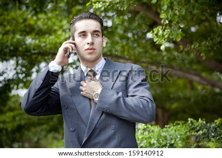 young businessman holding his mobile phone against his ear,out door