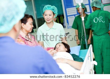 medical worker moving patient with her cousin on hospital trolley to operating room