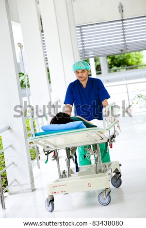medical worker moving patient on hospital trolley to operating room