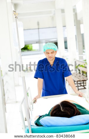 medical worker moving patient on hospital trolley to operating room