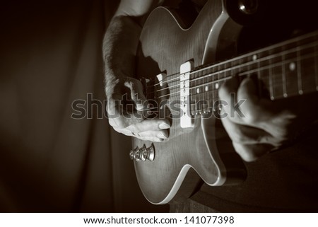 Man playing electric guitar at black background