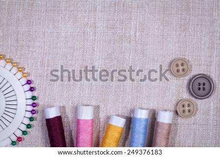 Buttons, bobbins with thread and needles on the old wooden background. Vintage Background