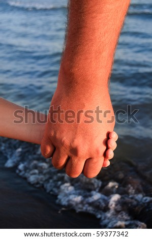 father lead by the hand son On the beach