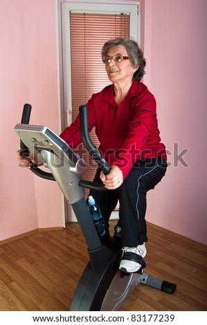 happy senior woman exercise on spinning bicycle at home
