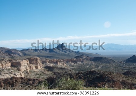 A typical Arizona landscape with desert, weathered rocky buttes and distant mountain peaks.
