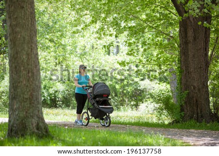 Young mother pushing a stroller in the park