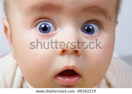 head shoot of cute baby with blue eyes and surprise look
