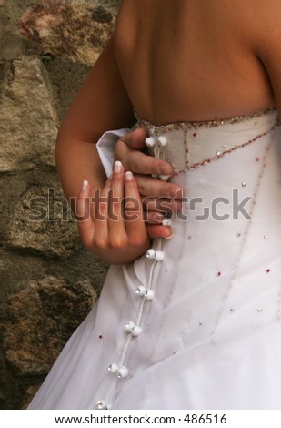 Bride holding grooms hand behind her back