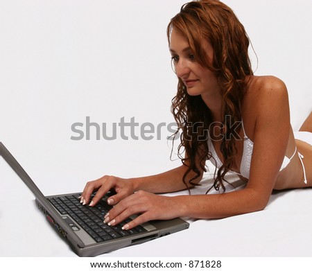 Woman in bikini laying on ground working on her computer