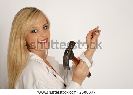 A woman hammering a nail into the wall