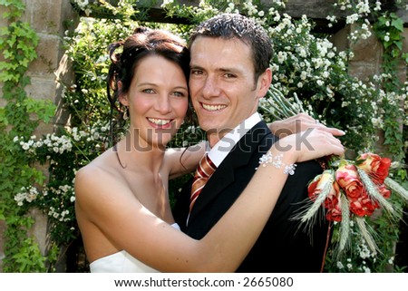 A bride standing with her arms around groom