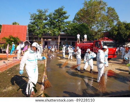 ANGTHONG, THAILAND - NOVEMBER 18: Volunteers from Bangkok help mop and clean the public school\'s court floor from all dirt and mud that came with the big flood in Angthong, Thailand on November 18, 2011.