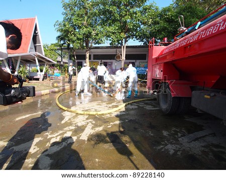 ANGTHONG, THAILAND - NOVEMBER 18: Volunteers from Bangkok help mop and clean the public school's court floor from all dirt and mud that came with the big flood in Angthong, Thailand on November 18, 2011.