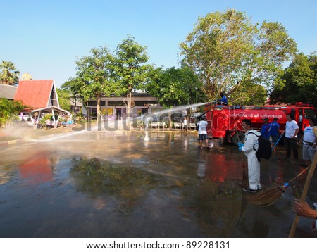 ANGTHONG, THAILAND - NOVEMBER 18: Volunteers from Bangkok help mop and clean the public school\'s court floor from all dirt and mud that came with the big flood in Angthong, Thailand on November 18, 2011.